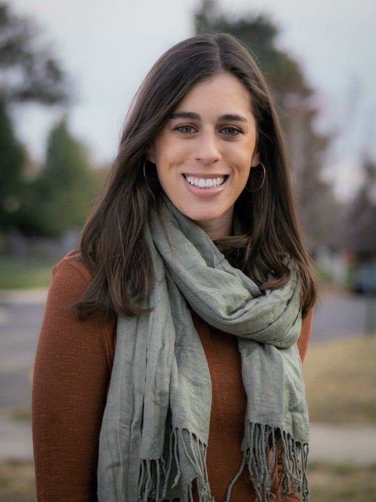 Emily Hirsch, a fair skinned woman with brown hair, in a brown sweater and gray scarf