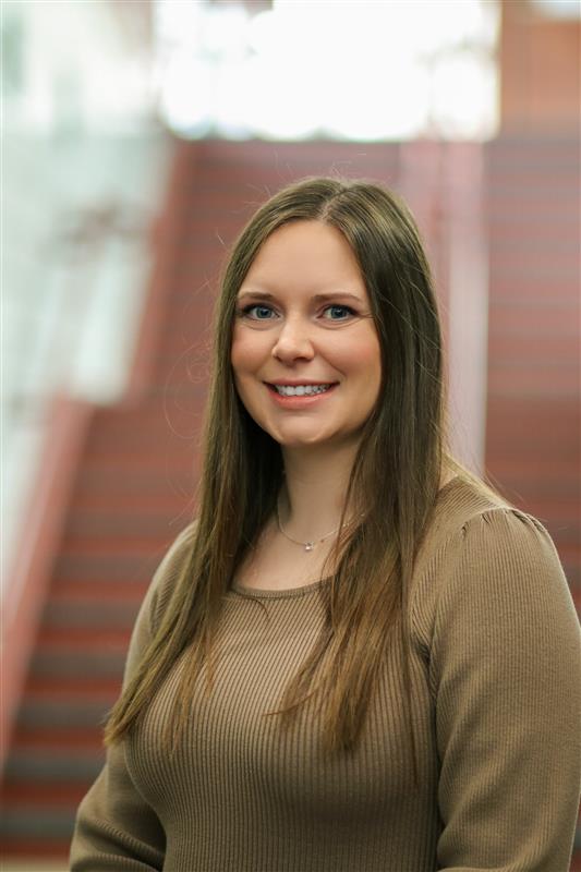 Joni Rumsey, a white woman with dark hair, wearing a brown shirt