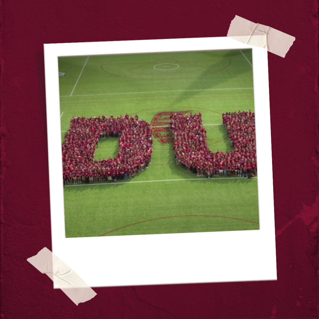 polaroid of Students in red shirts have stood in a pattern to make the letters D U as seen from above