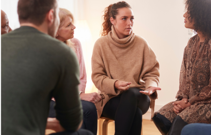 a group of people sit in a circle in a group session