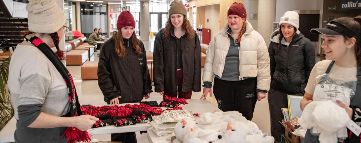 undergraduate girls gather around a promo table at Community Commons