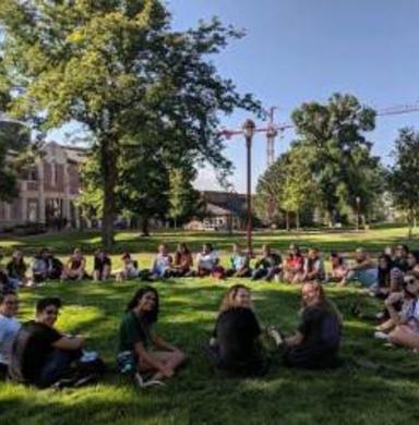 students sit in a circle on the green